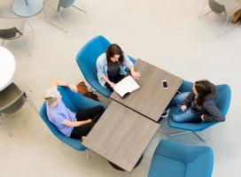 A top-down view of a group of students sitting at a table together studying